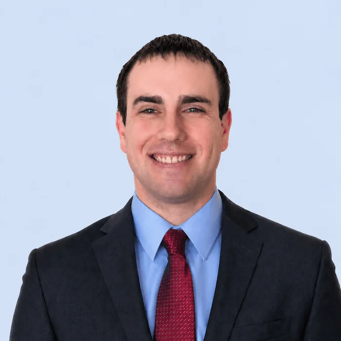 Headshot of Alex Winger in a suit and tie.